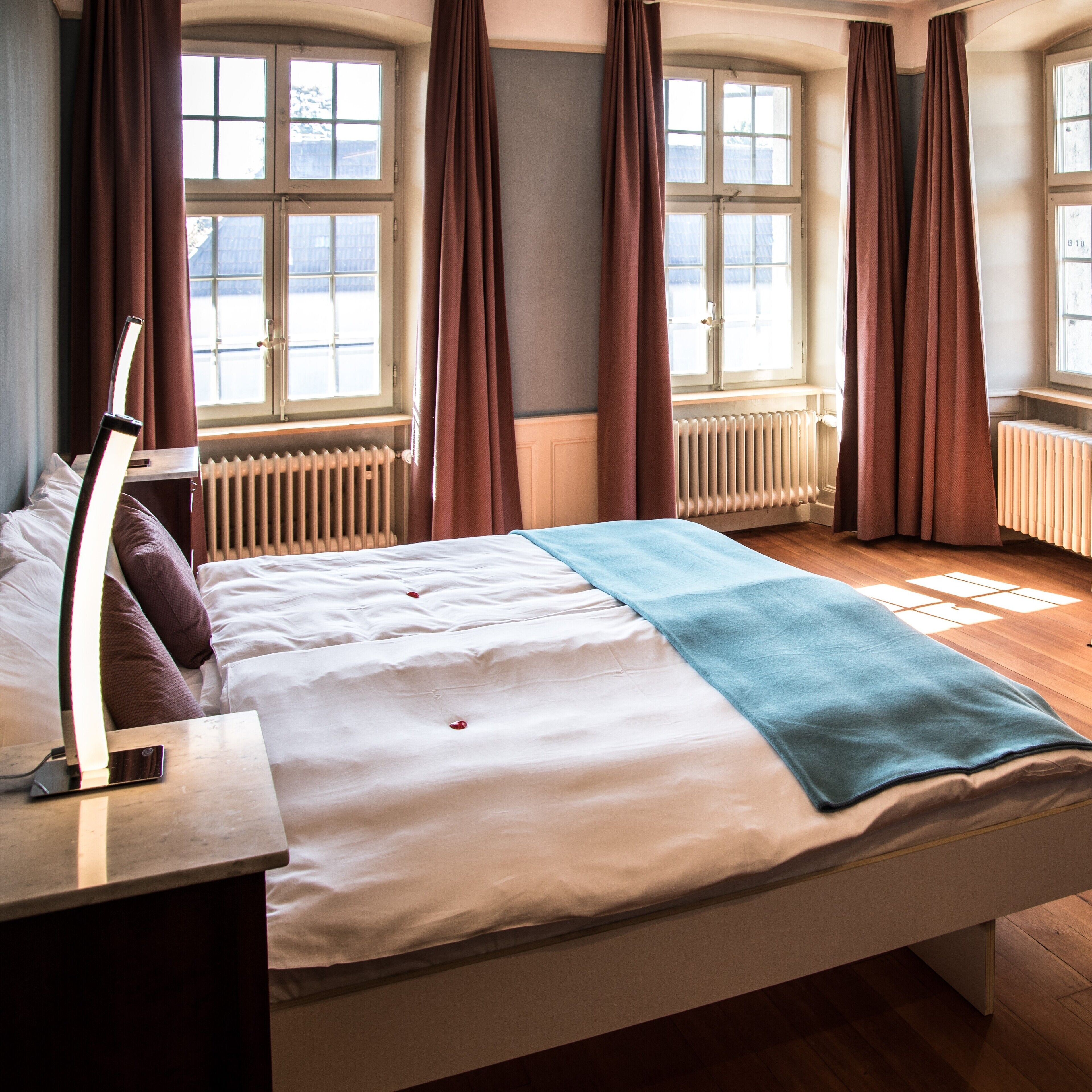 A bedroom with a bed, a nightstand, a lamp, and a window with curtains.
