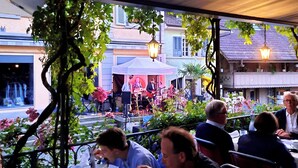 Un espace extérieur aménagé pour les repas, avec des tables et des chaises, entouré de verdure et de bâtiments.