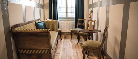 A cozy room with a wooden floor, a sofa, a chair, and a small table.