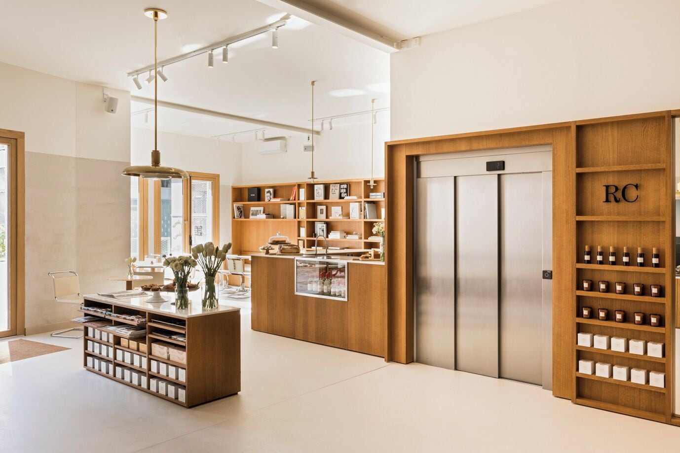 Un interior moderno con un mostrador de recepción, estanterías de madera y un ascensor de servicio.