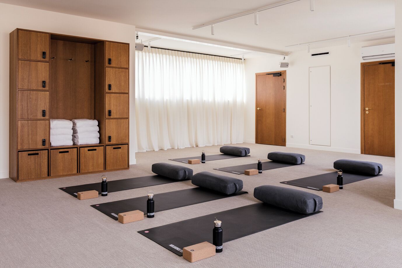 A yoga room with mats, blocks, and a wooden cabinet with towels.