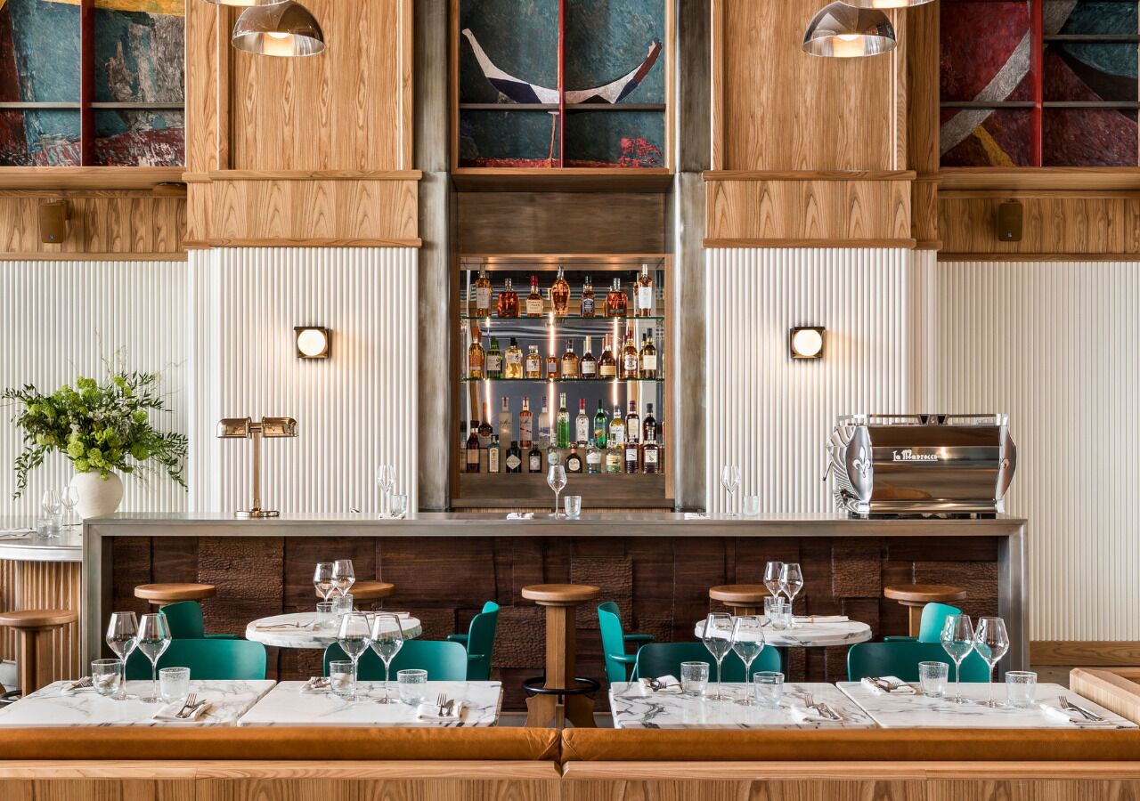 Ein Restaurant mit Holzwänden, einer Bar mit Flaschen und blaugrünen Stühlen.