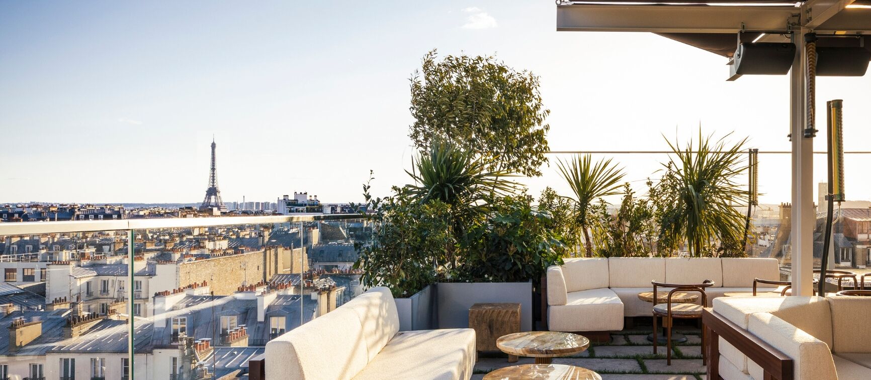 Eine Dachterrasse mit Blick auf den Eiffelturm, ausgestattet mit Sitzgelegenheiten und Pflanzen.