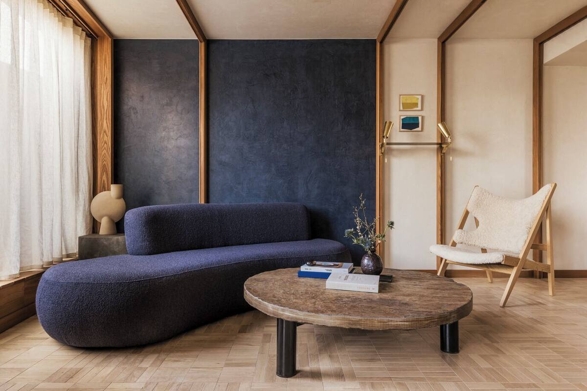 A modern living room with a sectional sofa, a round coffee table, a wooden floor, and a chair.