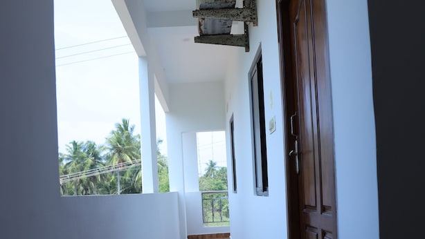 A corridor with a wooden floor, white walls, and a wooden door. - La Bell Residency Near Auroville Beach (Vanur)