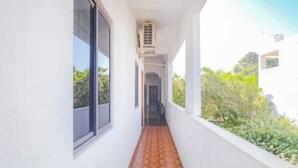 A narrow corridor with a wooden floor, large windows, and a view of greenery outside. - La Bell Residency Near Auroville Beach (Vanur)