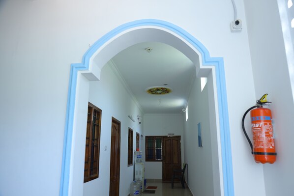 Un pasillo con un arco azulado, puertas de madera y un extintor en la pared.