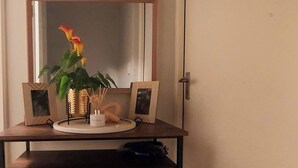 A desk with a mirror, two framed pictures, a plant, and a candle holder in a hallway. - Room-your Peaceful Haven, Unique Shared (Cape Town)