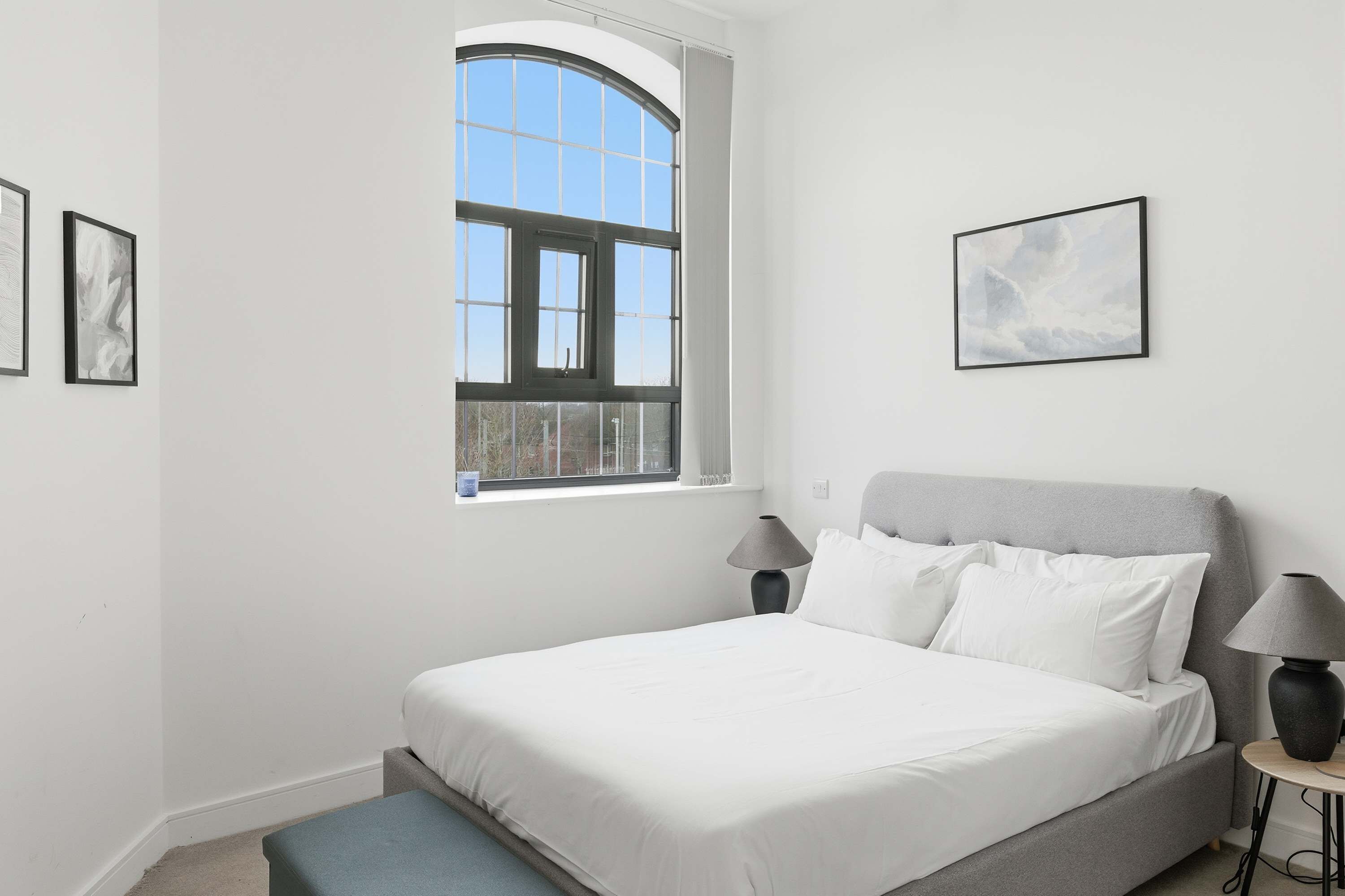 Quarto com uma cama grande, janela com vista e duas luminárias de cabeceira.