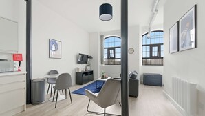 A modern, well-lit room with a dining area, a TV, and a large window providing natural light. - Characterful Apartment in Central Nottingham (Nottingham)