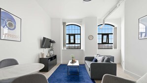 A modern living room with a dining table, grey sofas, and a blue rug. - Characterful Apartment in Central Nottingham (Nottingham)