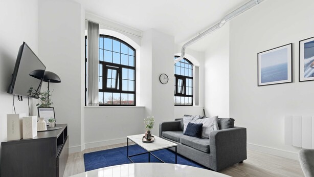 A modern living room with a grey sofa, a coffee table, a TV, and large windows. - Characterful Apartment in Central Nottingham (Nottingham)