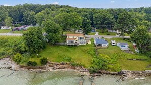 A large house with a spacious backyard, a dock, and a view of the water. - Lake Erie Getaway - Sunset Deck + Near GOTL Strip (Geneva)