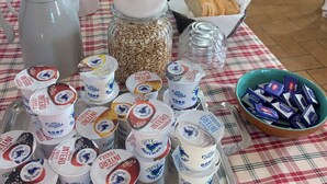 Una mesa de desayuno con diversos alimentos, como botes de cereales, una jarra y recipientes de yogur.