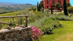 Una villa roja con una escalera de piedra y vistas a un viñedo.