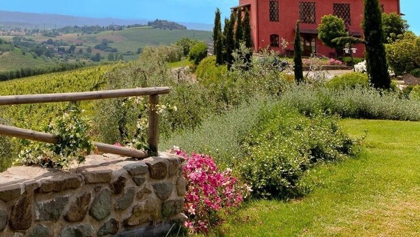 Una villa roja con una escalera de piedra y vistas a un viñedo.