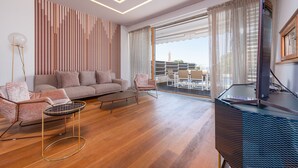 Un salon moderne avec un canapé, des fauteuils, une table basse et un téléviseur posé sur un meuble.