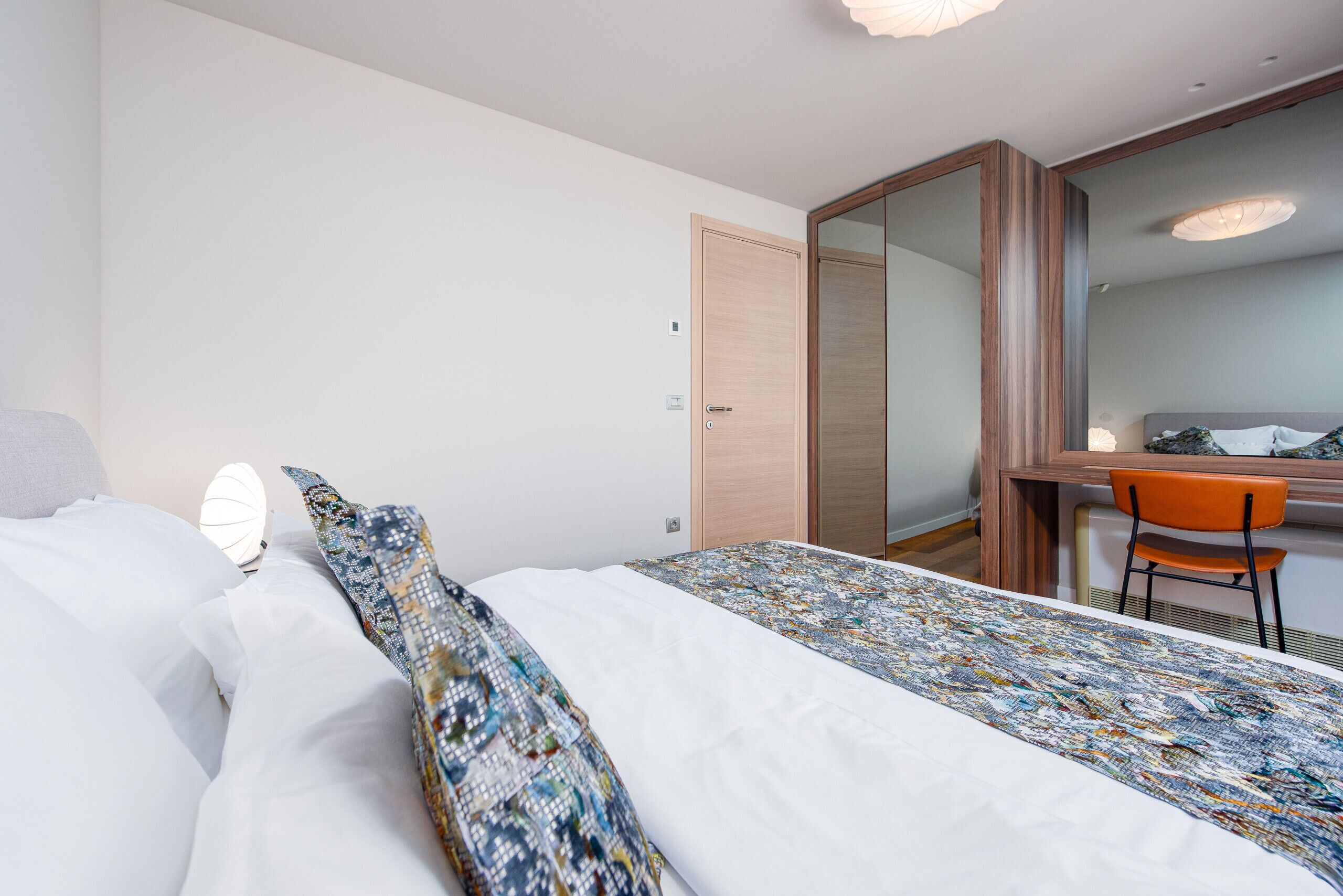 A hotel room with a bed, a desk, and a chair.