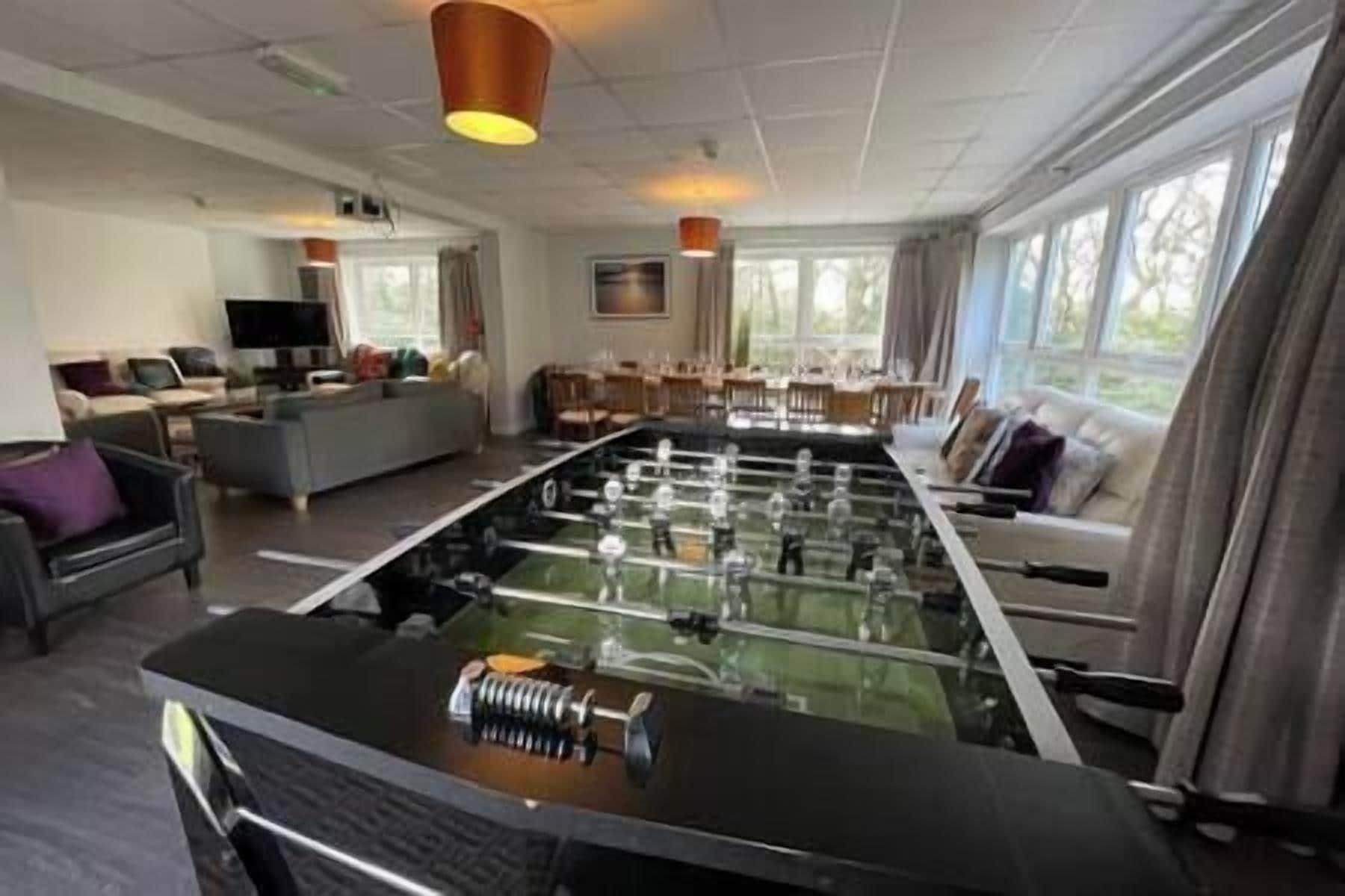 A spacious living area with a foosball table, a sofa, and a television.