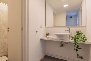 Une salle de bain moderne avec un lavabo blanc, un miroir et une plante en pot.