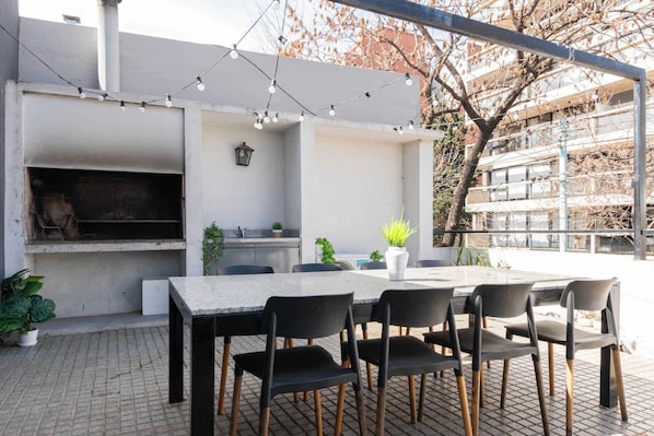 Eine Terrasse im Freien mit Grill, Sitzgelegenheiten und Lichterketten.