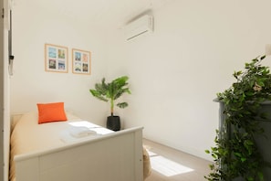 Un dormitorio con cama, planta en maceta y aire acondicionado de pared.