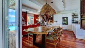 Una cocina moderna con una amplia mesa de comedor de madera, sillas tapizadas en rojo y una lámpara colgante de paja.