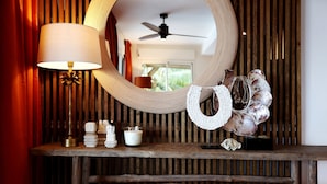 Un tocador de madera con un espejo redondo, una lámpara y conchas decorativas.