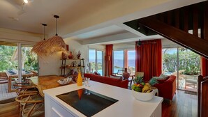 Una cocina moderna con una isla central, zona de comedor con sillas de madera y vistas al exterior.