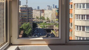 A view from a window of a multi-story building with a street scene below, including parked cars and a bridge. - Andreea (Bucharest)