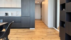 A modern kitchen with dark cabinetry, a wooden floor, and pendant lighting. - Joy City Stay Nord One N2-52 (Timișoara)