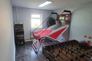 A room with a foosball table, a window, and a bookshelf. - 17 Bedroom Huge Holiday Home.  When SIZE is important. (Bontnewydd)