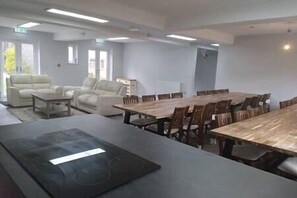 A conference room with a large table and several chairs, a sofa, and a coffee table. - 17 Bedroom Huge Holiday Home.  When SIZE is important. (Bontnewydd)