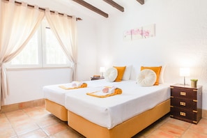 A double bed with white and orange bedding, a nightstand with a lamp, and a window with curtains. - Villa Dreams (Albufeira)