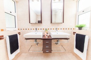 A bathroom with two sinks, a mirror, a towel rack, and a small plant. - Villa Dreams (Albufeira)