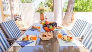 A table set for breakfast with a fruit bowl, plates of food, and drinks. - Villa Dreams (Albufeira)