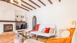 A living room with a fireplace, white sofas, a coffee table, and a bookshelf. - Villa Dreams (Albufeira)