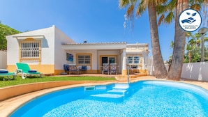A pool area with a white building, a covered seating area, and a palm tree. - Villa Dreams (Albufeira)