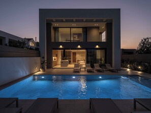Una piscina al aire libre, sombrillas, sillones reclinables de piscina