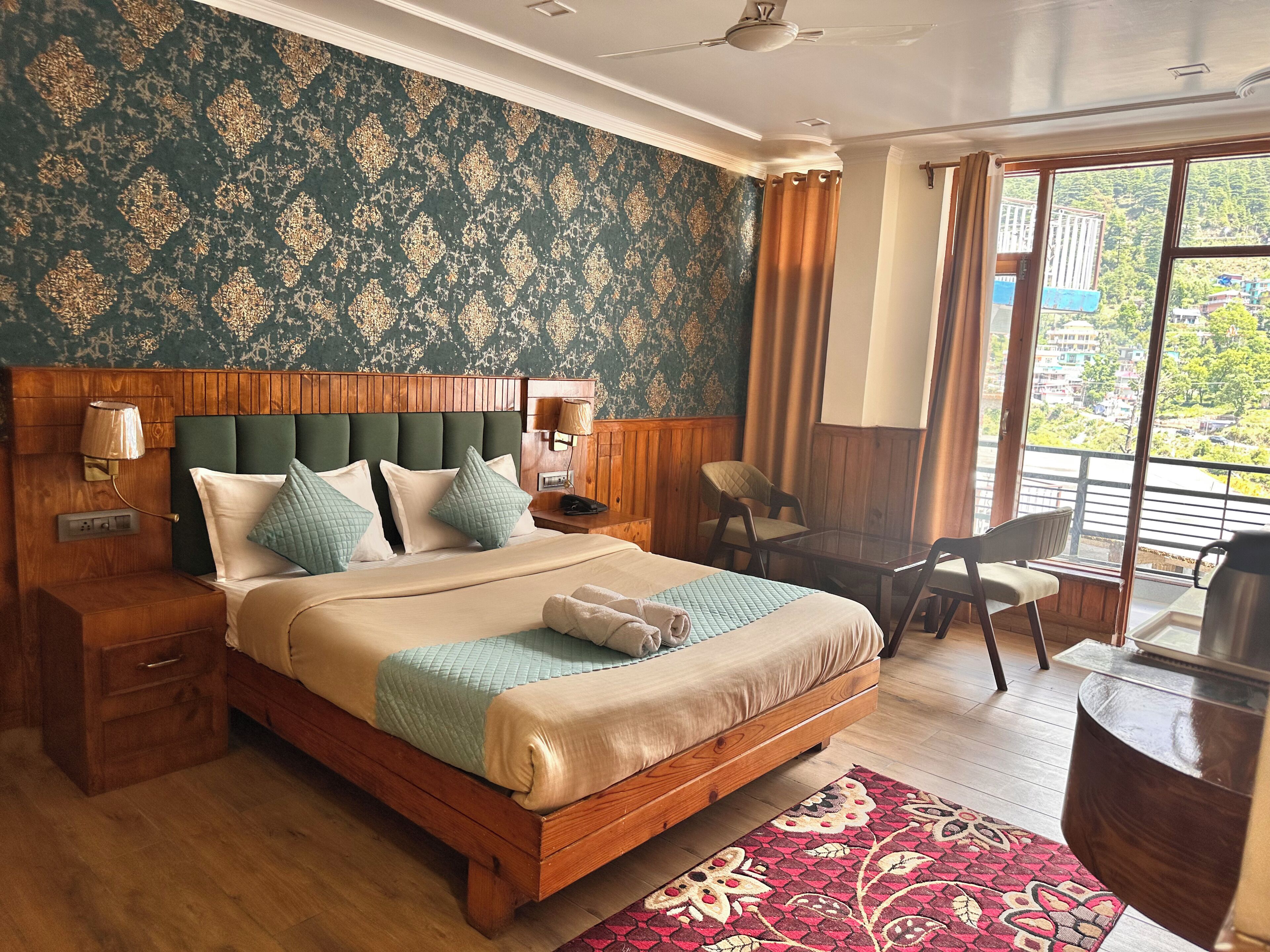 A hotel room with a wooden bed, a desk, a chair, a window with a view, and a patterned wall.