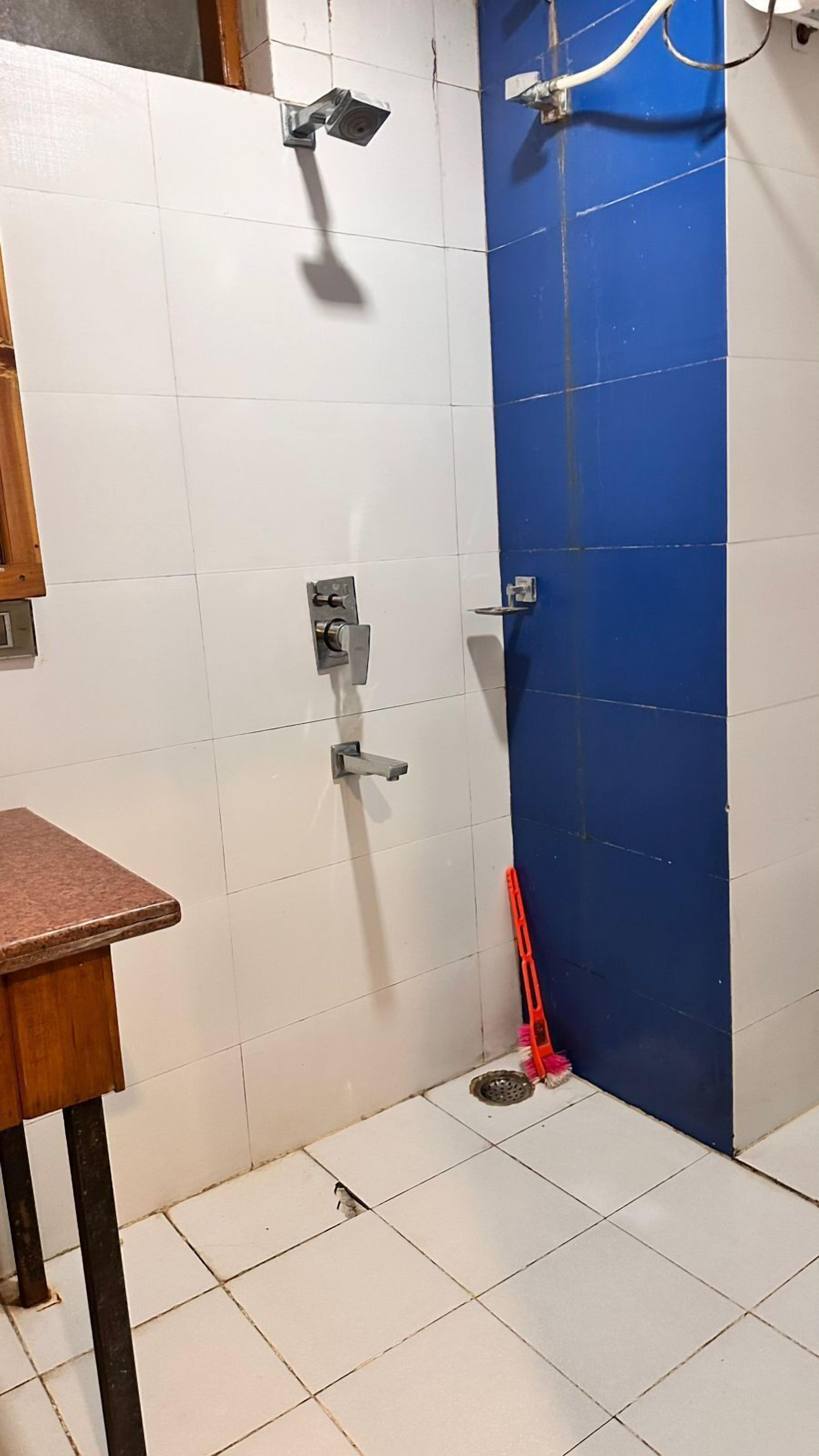 Un baño con azulejos blancos y azules, una ducha, un inodoro y un lavabo.