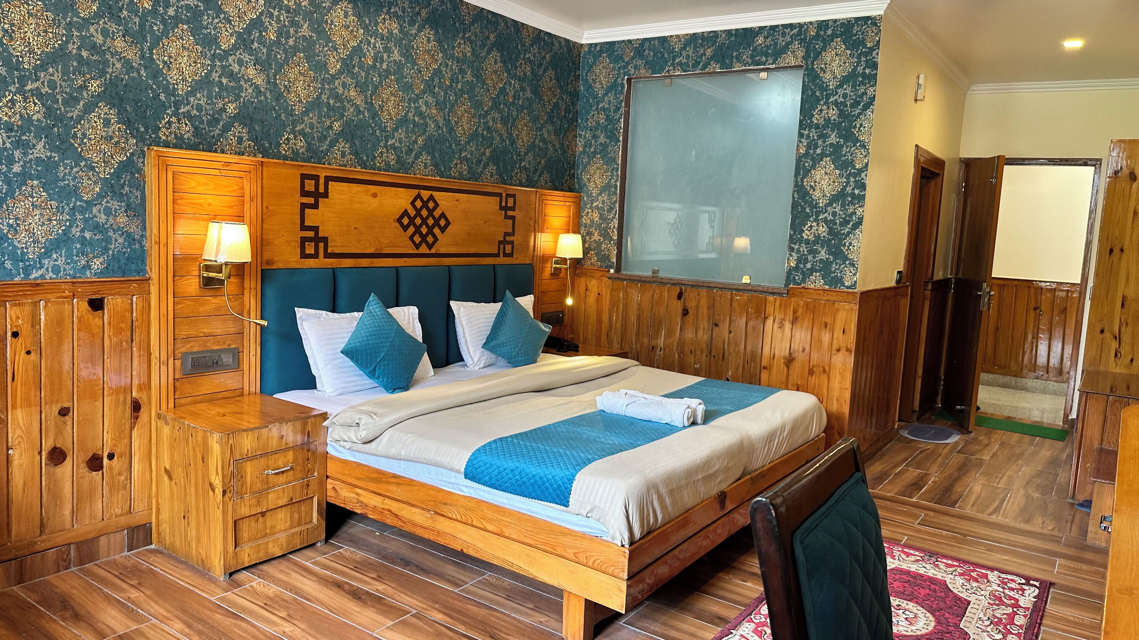 A wooden bed with a headboard, bedside tables, a mirror, and a door.