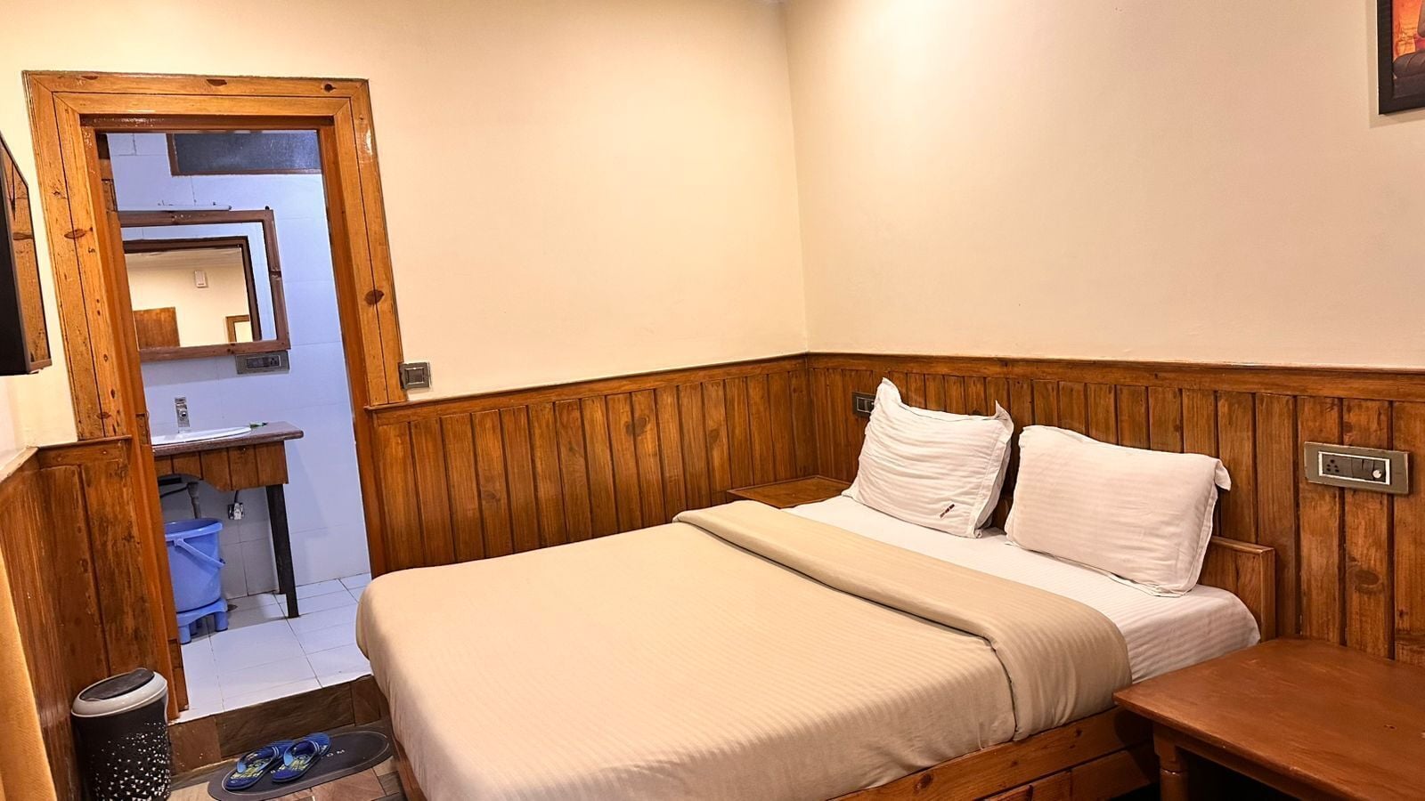 A bedroom with a wooden headboard, a bed with white bedding, a small bedside table, and a wooden nightstand.