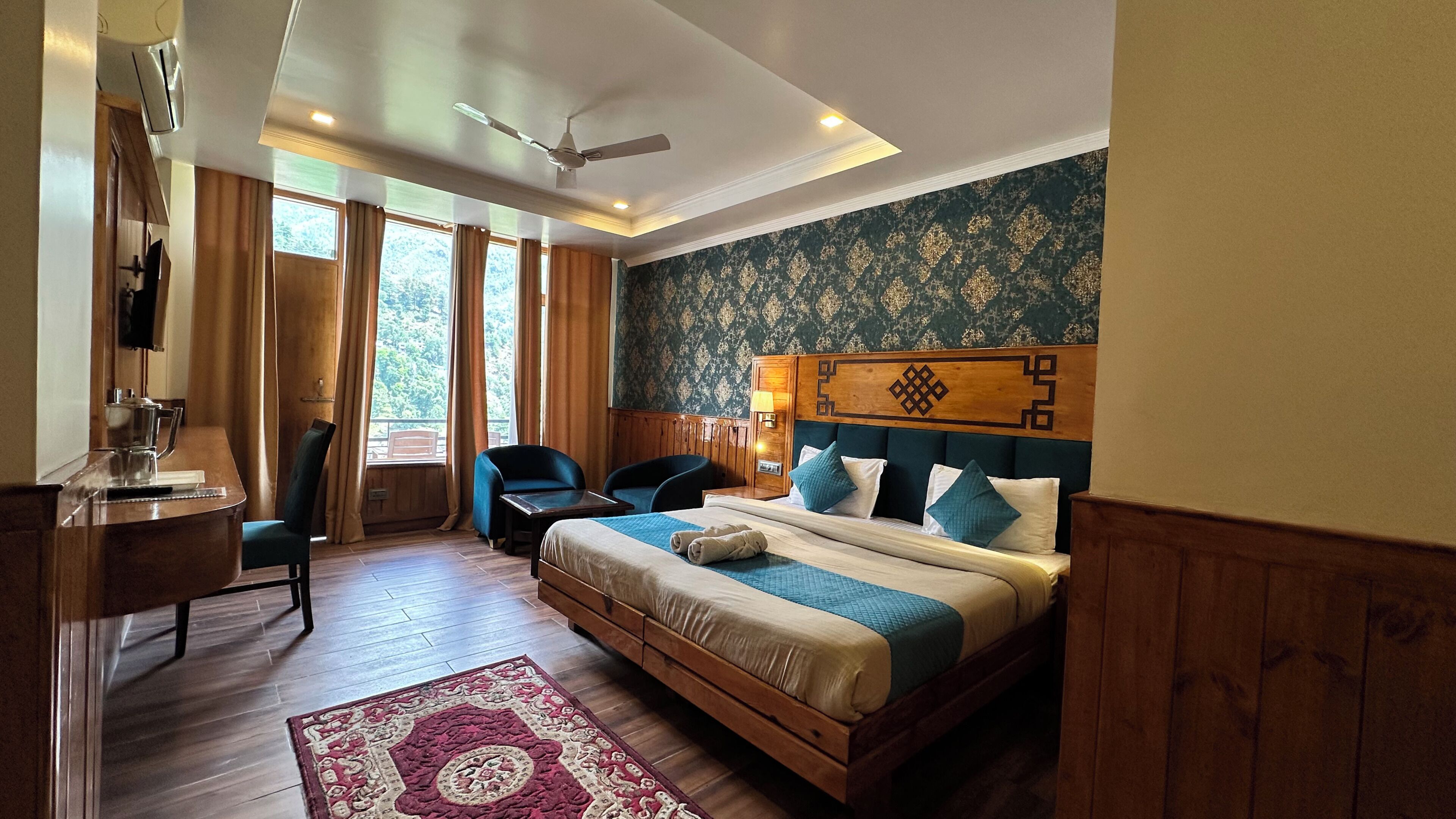 A hotel room with a bed, a desk, a chair, a television, and a view of the outdoors.