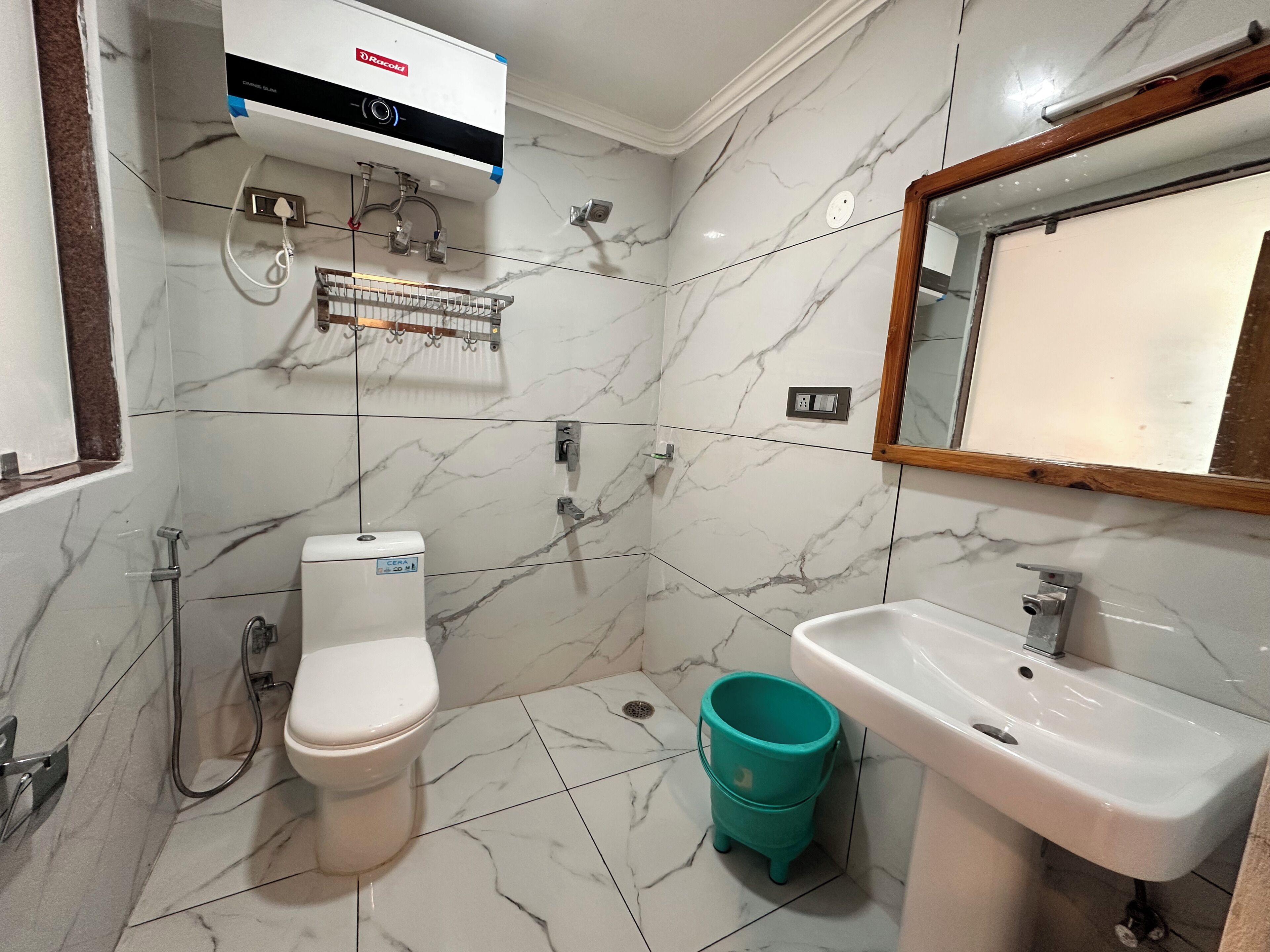 A bathroom with a toilet, a sink, a mirror, a shower, and a wall-mounted air conditioning unit.