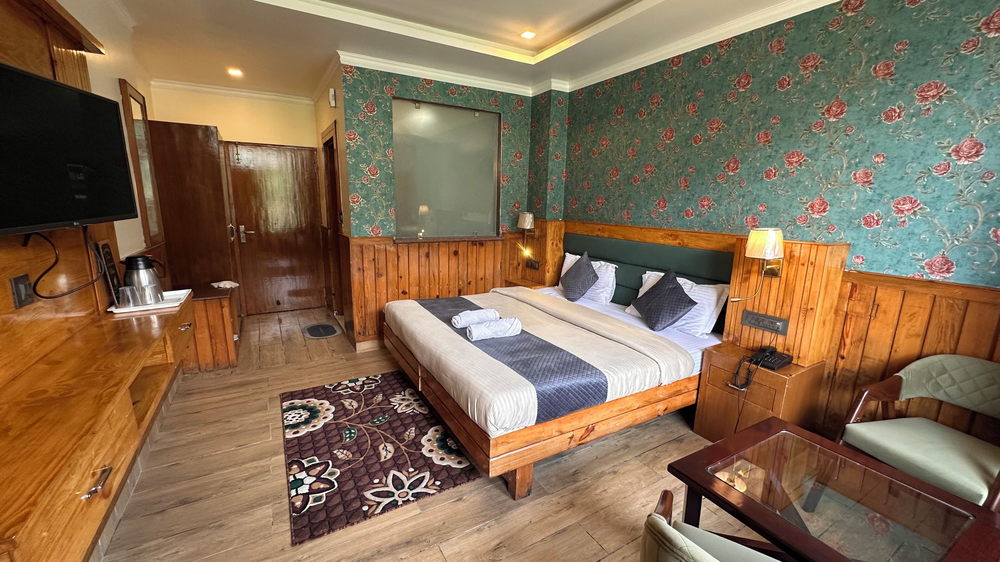 A hotel room with a wooden bed, a television, a desk, and a chair.