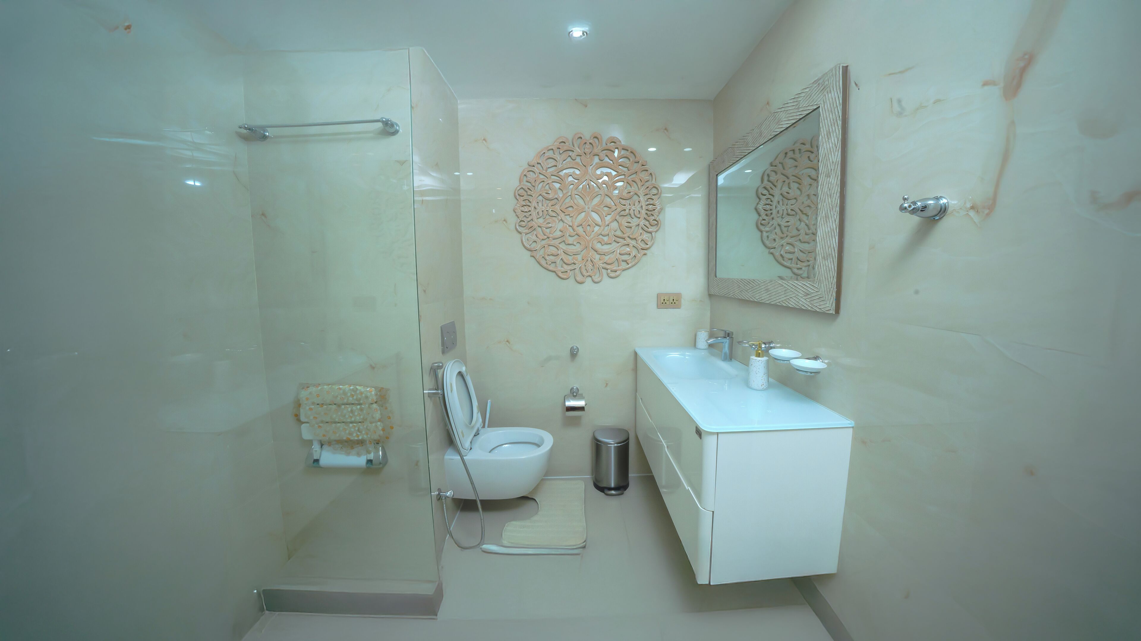 Een moderne badkamer met een douchecabine van glas, een toilet, een wastafel met spiegel en decoratieve wanddecoratie.