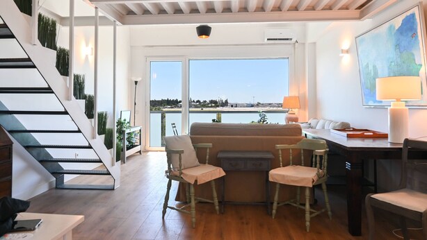 Un interior moderno con una escalera, una zona de estar con vistas al exterior y una mesa de comedor.