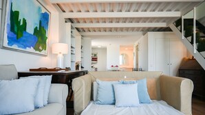Una sala moderna con un sofá, una cama, una lámpara y una escalera.