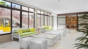 A spacious living area with a staircase, white furniture, and large windows. - Saint George Apartamentos      (Arona)